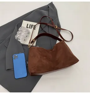 Détails du sac bandoulière en daim marron avec double sangle et boucles dorées
