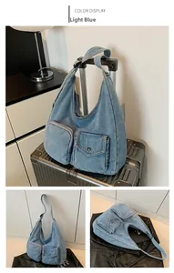 Sac hobo en jean bleu clair avec deux poches avant, illustré sur une valise de voyage