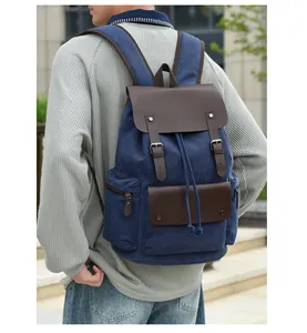 Detail of blue canvas backpack with brown leather flap and adjustable shoulder straps