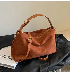 Vue détaillée de la texture en daim marron et des ferrures dorées du sac Boston rétro