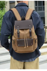 Detail view of a vintage canvas backpack with leather straps and multiple pockets on a model