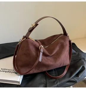 Détail du sac Boston en daim marron foncé avec fermeture éclair dorée et anse en cuir