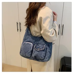 Détail du sac cabas en jean bleu avec poches avant fonctionnelles et texture délavée