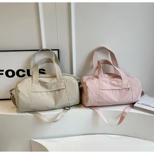 Dettaglio di borse da viaggio in nylon impermeabile beige e rosa con tracolla regolabile