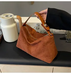 Détail du sac Boston en daim marron avec poignées en cuir et fermeture éclair