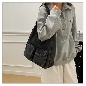 Détail du sac hobo en jean noir avec poches cargo et finition délavée vintage