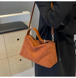 Détail d'un sac Boston en daim marron avec poignées en cuir lisse et boucles argentées