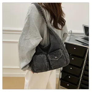Détail du sac fourre-tout en denim gris montrant les poches et la boucle métallique