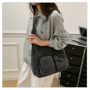 Vue détaillée du sac bandoulière en denim foncé avec doubles poches frontales pratiques
