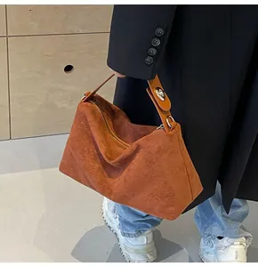 Gros plan d'un sac Boston en daim caramel sur un modèle portant un manteau noir chic