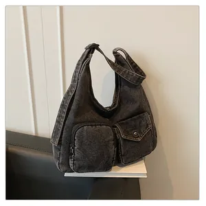Détail du sac hobo en jean gris foncé avec doubles poches utilitaires et bandoulière réglable