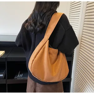 Detalle del bolso hobo grande de ante color caramelo con correa ancha sobre modelo