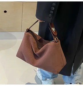 Vue détaillée du sac Boston en daim marron avec boucles dorées et poignée en cuir élégante
