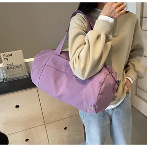 Dettaglio della borsa da viaggio viola in nylon impermeabile indossata a spalla dal modello