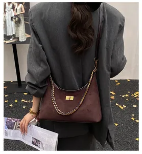 Détail du sac à bandoulière en daim marron avec fermoir doré et bandoulière chaîne
