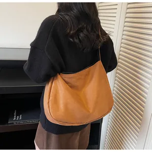 Bolso tote de ante marrón en el hombro de la modelo con un estilo vintage minimalista