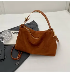 Détail du sac Boston en daim caramel avec finitions dorées et bandoulière réglable