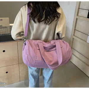 Vista posteriore della borsa da viaggio viola in nylon con manici spessi e tracolla rimovibile