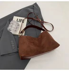 Détail du sac Boston en daim marron avec bordures en cuir lisse et boucles dorées