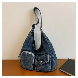 Détail du sac fourre-tout en denim délavé avec deux poches avant et texture vintage