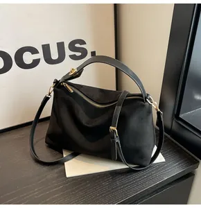 Détail du sac Boston en daim noir avec fermeture éclair dorée et bandoulière