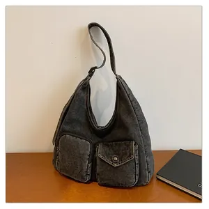 Détail du sac hobo en jean noir délavé avec poches asymétriques et pressions métalliques