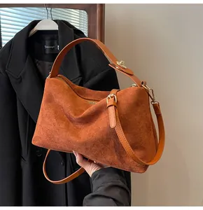 Gros plan d'un sac Boston en daim caramel avec détails dorés et bandoulière