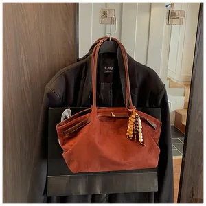 Detail einer rotbraunen Wildleder-Tragetasche mit Holzperlen-Anhänger am Blazer