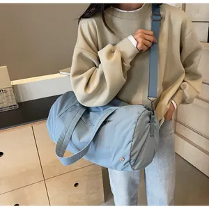 Dettaglio borsa da viaggio in nylon celeste con tracolla su una modella femminile