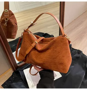 Détail du sac Boston en daim marron avec boucles en métal doré et poignée en cuir lisse
