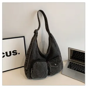 Détail du sac fourre-tout en denim gris foncé montrant les poches et le style urbain rétro