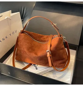 Détail du sac Boston en cuir mat marron dans un coffret cadeau avec boucles dorées
