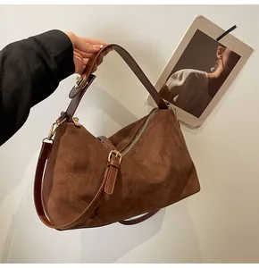 Détails macro du sac Boston en daim caramel avec finitions dorées et cuir lisse