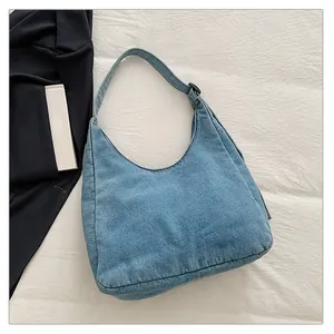 Détail de la texture du sac hobo en jean bleu clair et de la boucle de bandoulière
