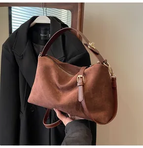 Détail du sac Boston en daim marron montrant la texture douce et les finitions dorées