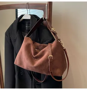Détail du sac Boston en daim marron avec bandoulière en cuir et boucle en métal doré