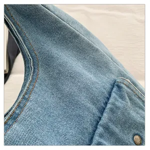 Gros plan sur la texture du denim bleu clair et la couture orange de ce sac à main