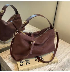 Gros plan du sac Boston en daim marron foncé avec fermeture éclair dorée et verrou rotatif