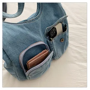 Détail du sac fourre-tout en jean bleu clair montrant le smartphone et le portefeuille