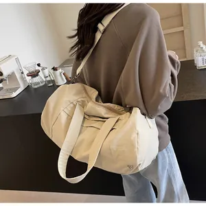 Foto lifestyle di una borsa da viaggio grande in nylon beige indossata da una modella