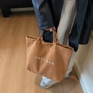 Brown suede tote bag with white TOTE BAG lettering in a stylish urban commuter style