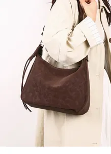 Detail of dark brown suede hobo bag with braided knot strap and matte vintage texture