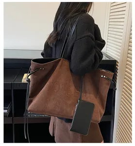 Détail du cabas en suédine avec lettrage embossé et une pochette zippée assortie