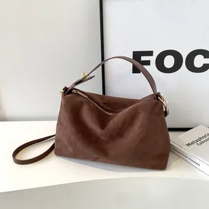 Détail du sac Boston en daim marron foncé avec fermeture éclair dorée élégante