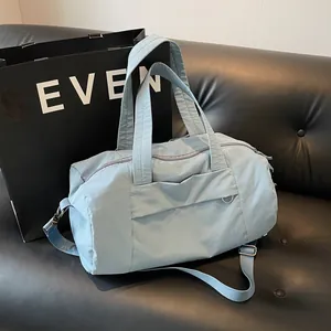 Borsa da viaggio in nylon impermeabile azzurro con tracolla su divano nero