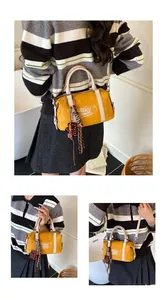 Detail of yellow Boston bag showing the adjustable strap, bear print, and side charm