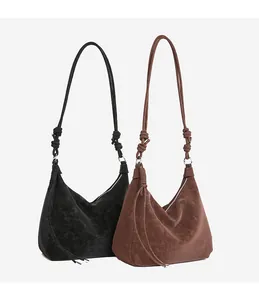 Detailed view of vintage suede hobo bags in black and brown with knotted strap accents
