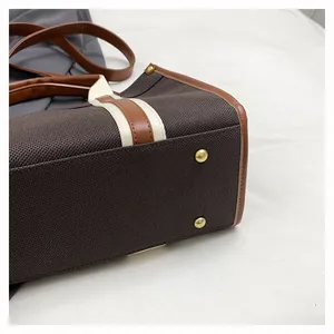 Detail of canvas tote bag featuring leather trim and protective gold studs on the bottom