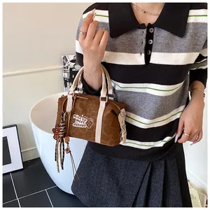 Detail view of brown leopard pattern Boston bag with cream handles and tassel charm