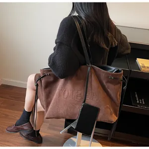 Détail du sac cabas en daim marron foncé avec embossage TOTE BAG et une petite pochette